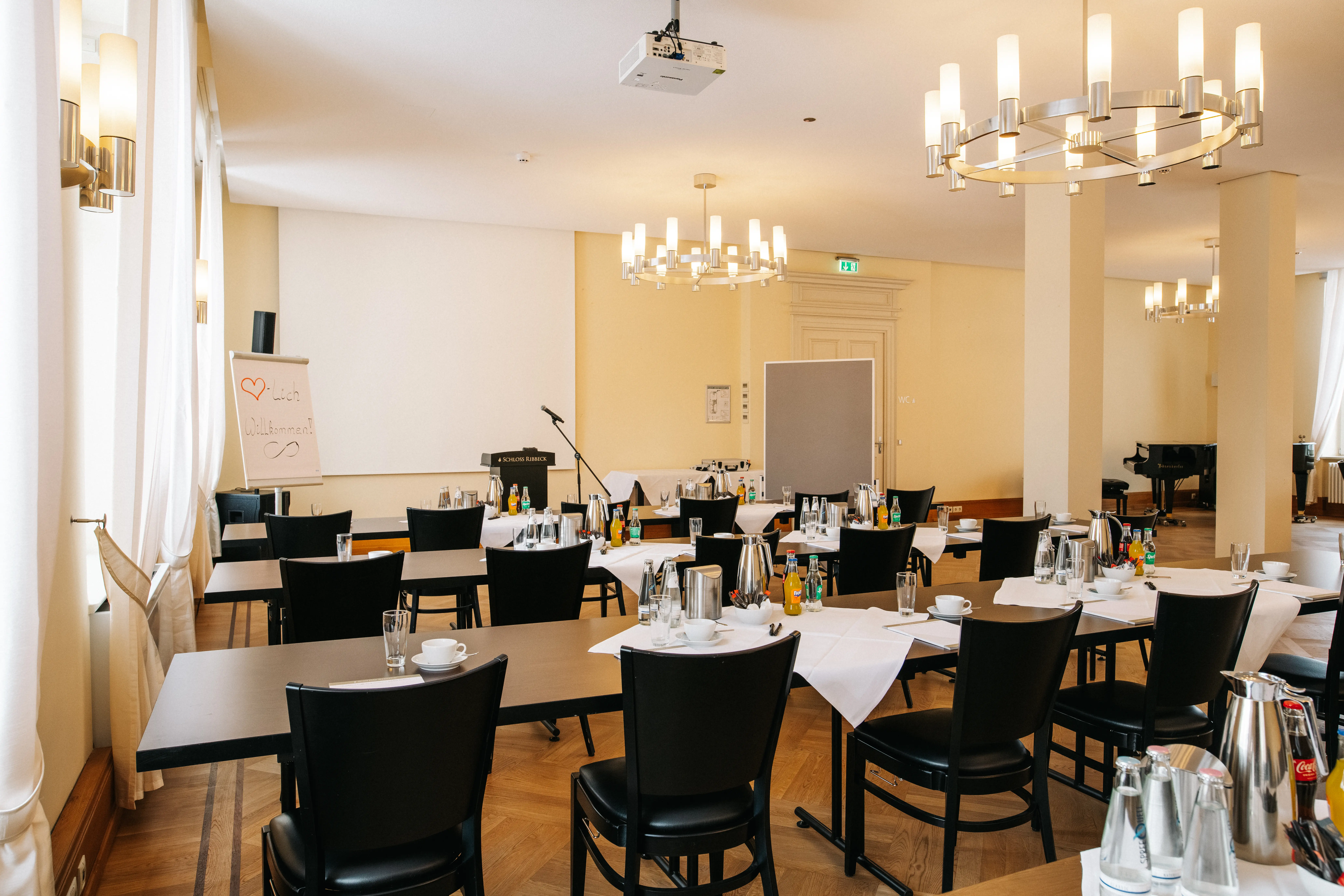 Seminarraum auf Schloss Ribbeck mit Tischen, Leinwand und Tageslicht