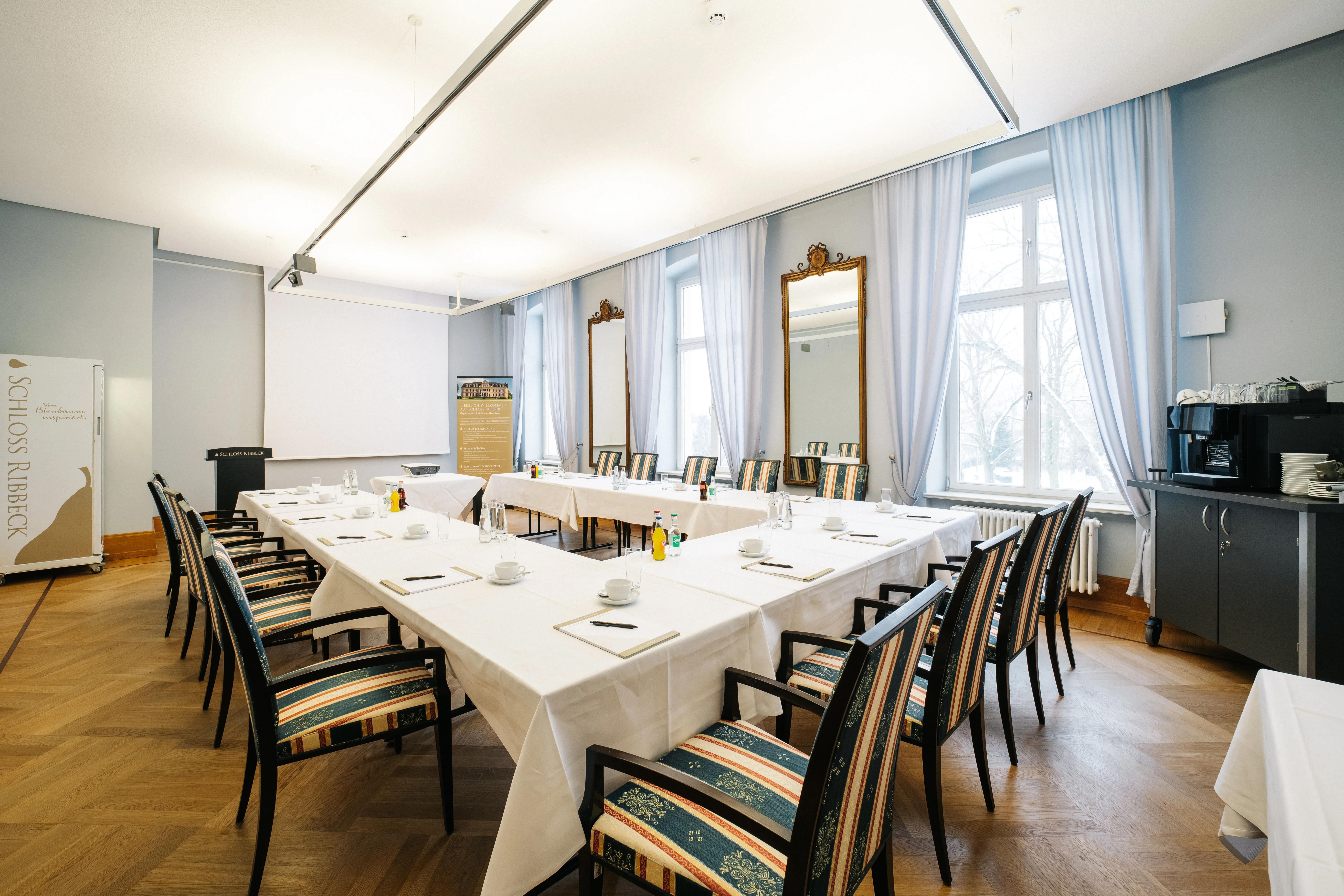 Tagungsraum auf Schloss Ribbeck mit gedeckten Tischen und Pausenbereich